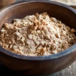A freshly baked apple crumble in a rustic baking dish, featuring a golden, crispy topping and a warm, bubbling fruit filling, served with a scoop of vanilla ice cream on top.